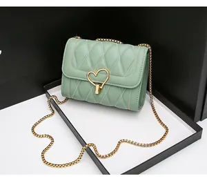 Détail d'un sac bandoulière matelassé vert avec fermoir rotatif doré en forme de cœur