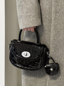 Détail du sac à main noir en cuir verni gaufré crocodile avec fermoir rotatif en métal argenté