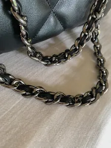 Close-up of black quilted leather tote bag with silver metal chain strap detail