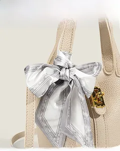 Detailed macro of beige lychee grain leather handbag with gold lock and silk scarf detail