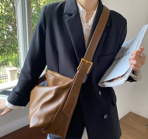 Detail of brown leather hobo bag with adjustable strap and golden buckle buckle