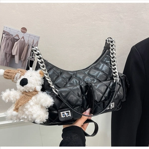 Détail d'un sac à bandoulière en cuir noir matelassé avec chaîne argentée et ourson