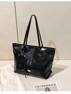 Detail view of large black tote bag with glossy texture and a small zip pouch