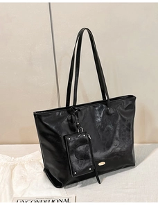 Detail of black glossy crinkled tote bag with thin straps and a detachable mini pouch