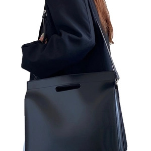 Minimalist large black leather tote bag with top handle and shoulder strap for women