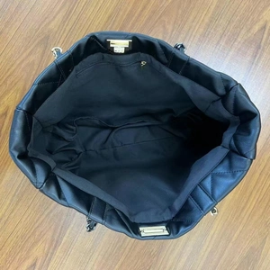 Interior view of black quilted tote bag showing zipper pocket and spacious layout