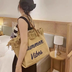Detail of woven straw tote bag with Summer Vibes embroidery and brown leather straps