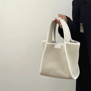 Detail of minimalist cream canvas tote bag with white leather trim and reinforced handle