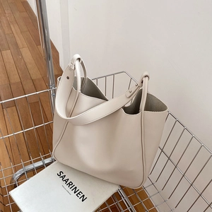 Minimalist beige leather tote bag displayed in a metal wire basket for a chic look
