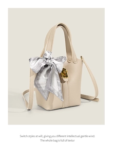 Detail of beige lychee grain leather bucket bag with silk scarf and gold lock