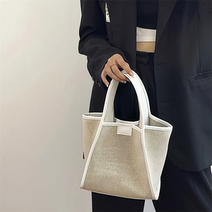 Detailed macro view of trapezoid canvas tote bag with white leather contrast trim and handle