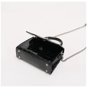 Dettaglio macro della borsa in pelle coccodrillo nera con chiusura magnetica argento