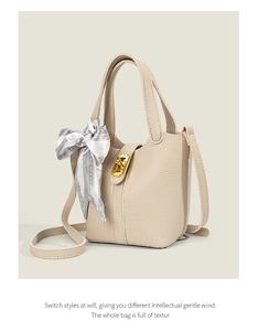 Detail of beige litchi grain leather bucket bag with silk scarf and gold metal lock