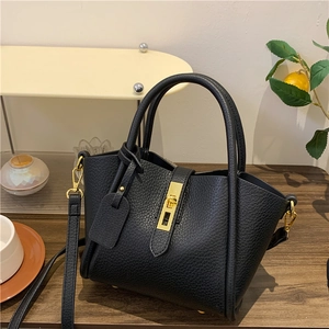 Sac fourre-tout chic en cuir noir à grain litchi avec détails dorés sur table
