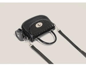 Détail d'un sac à bandoulière en cuir crocodile noir avec fermoir argenté et mini pochette