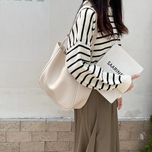 Minimalist cream tote bag styled as an underarm shoulder bag for modern daily commuting
