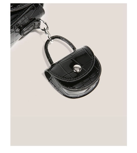 Détail d'une mini pochette noire à motif crocodile avec fermoir métallique argenté