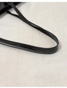 Close-up of the fine stitching and texture on the black leather shoulder bag strap