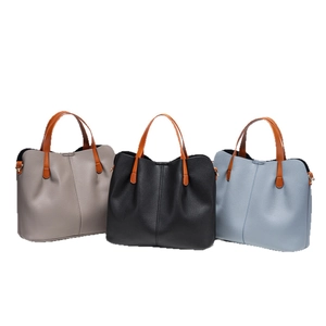 Three minimalist textured leather tote bags in grey, black and light blue with brown handles