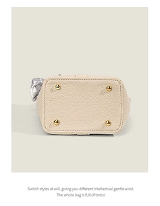 Bottom view of beige leather bucket bag featuring four protective gold metal feet studs
