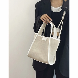 Minimalist canvas tote bag with leather trim and adjustable strap for women in off-white