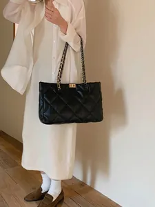Detail of classic black quilted tote bag with gold twist lock and metal chain strap