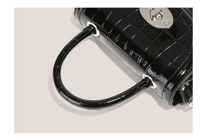 Gros plan du sac à main noir à motif crocodile avec fermoir rotatif argenté brillant