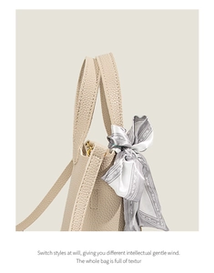 Detail of lychee pattern leather handbag with elegant printed silk scarf and gold hardware