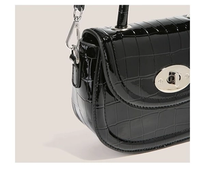 Détail du sac à main noir motif crocodile avec fermoir rotatif et accessoires argentés