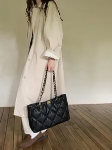Detail of black quilted leather tote with gold chain strap and turn-lock closure