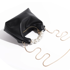 Close-up of black leather mini handbag with large pearl handle and gold chain strap