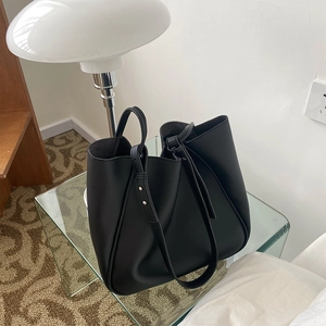 Close-up of black tote bag showing premium faux leather texture and knotted strap detail