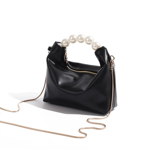 Close-up of black PU leather dumpling bag with large pearl handle and gold snake chain