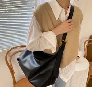 Close-up of black hobo bag with adjustable wide strap and metallic gold buckle detail
