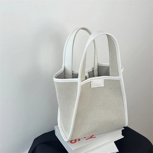 Detail of minimalist canvas tote bag with white leather trim and reinforced stitching