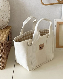 Detail of canvas tote bag with embroidered bear and brown checkered lining