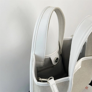 Detailed macro view of gray canvas tote bag stitching and silver magnetic closure