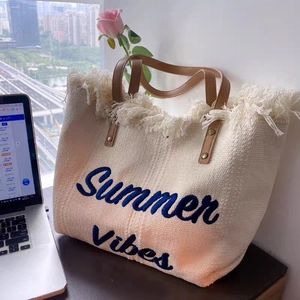 Close-up of bohemian canvas tote with Summer Vibes embroidery and fringe details