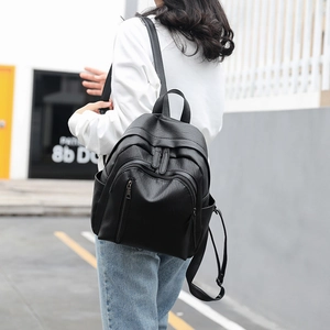 Classic large black leather backpack for women shown in a stylish outdoor street view