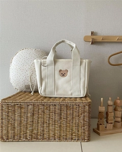 Detail of canvas bag with embroidered bear, drawstring interior, and metal D-ring attachment