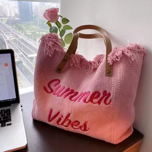 Pink woven tote bag with Summer Vibes embroidery and brown leather handles in a home setting