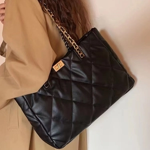 Quilted tote bag with chain strap and gold twist lock shown on model with trench coat