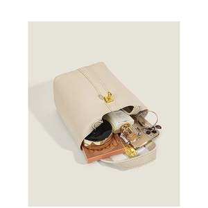 Chic beige pebbled leather bucket bag with top handle and gold hardware showing interior capacity