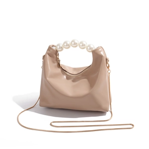 Detailed close-up of premium beige dumpling bag with pearl handle and gold chain strap
