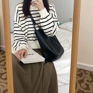 Detail view of the black matte leather tote bag styled with a striped knit sweater