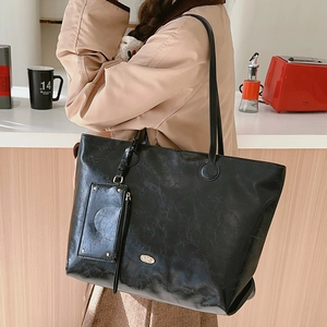 Minimalist black oil wax leather tote bag with a small pouch and golden logo detail