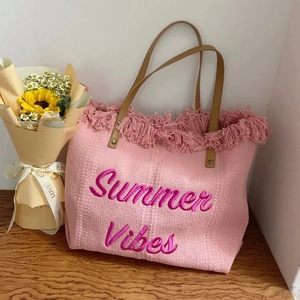 Pink canvas tote bag with Summer Vibes embroidery and fringe trim on a wooden background