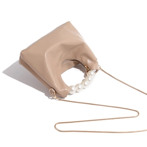 Detail of beige hobo bag with large pearl handle and golden snake chain strap