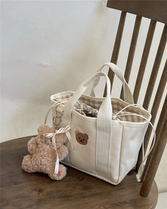 Detail of canvas mummy bag with bear embroidery and brown plaid drawstring lining