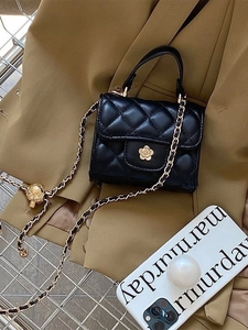 Dettaglio mini borsa trapuntata nera con chiusura a fiore dorato e tracolla a catena